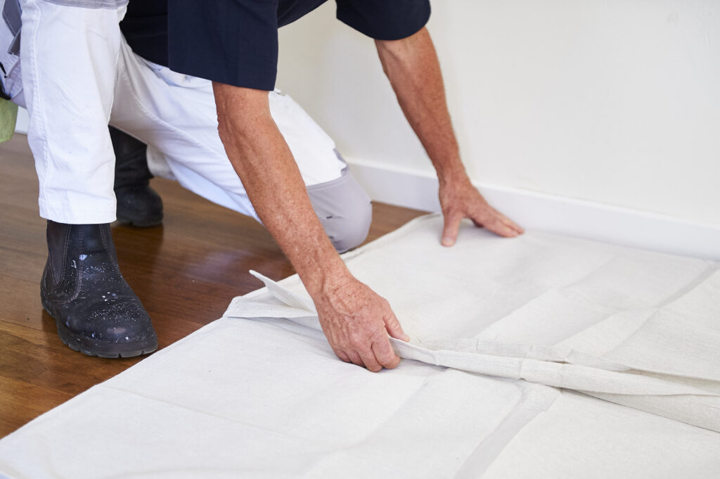 Person laying down protective covering for Paint an Interior Wall