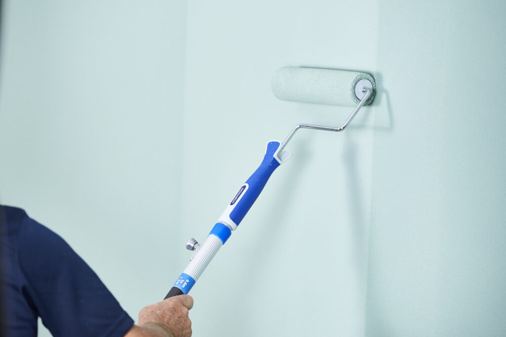 Person painting a wall with roller