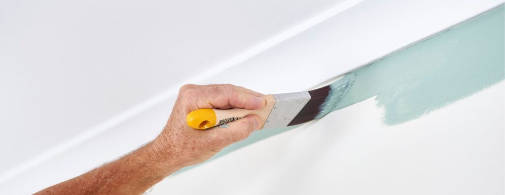 Hand painting a wall with brush Paint an Interior Wall